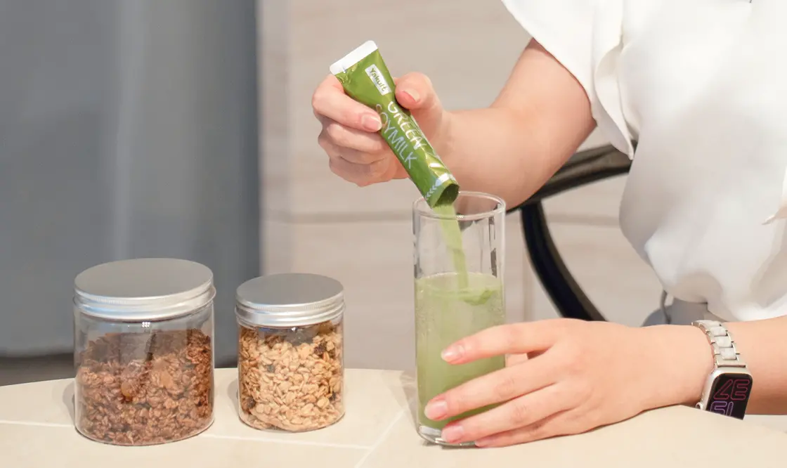 グリーンの粉末をスティックからグラスに注いでいる